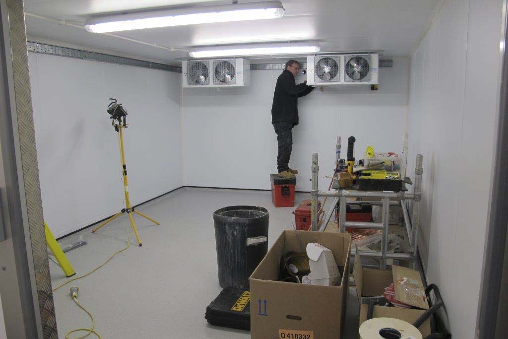 Man installing final parts of a walk in refrigerator